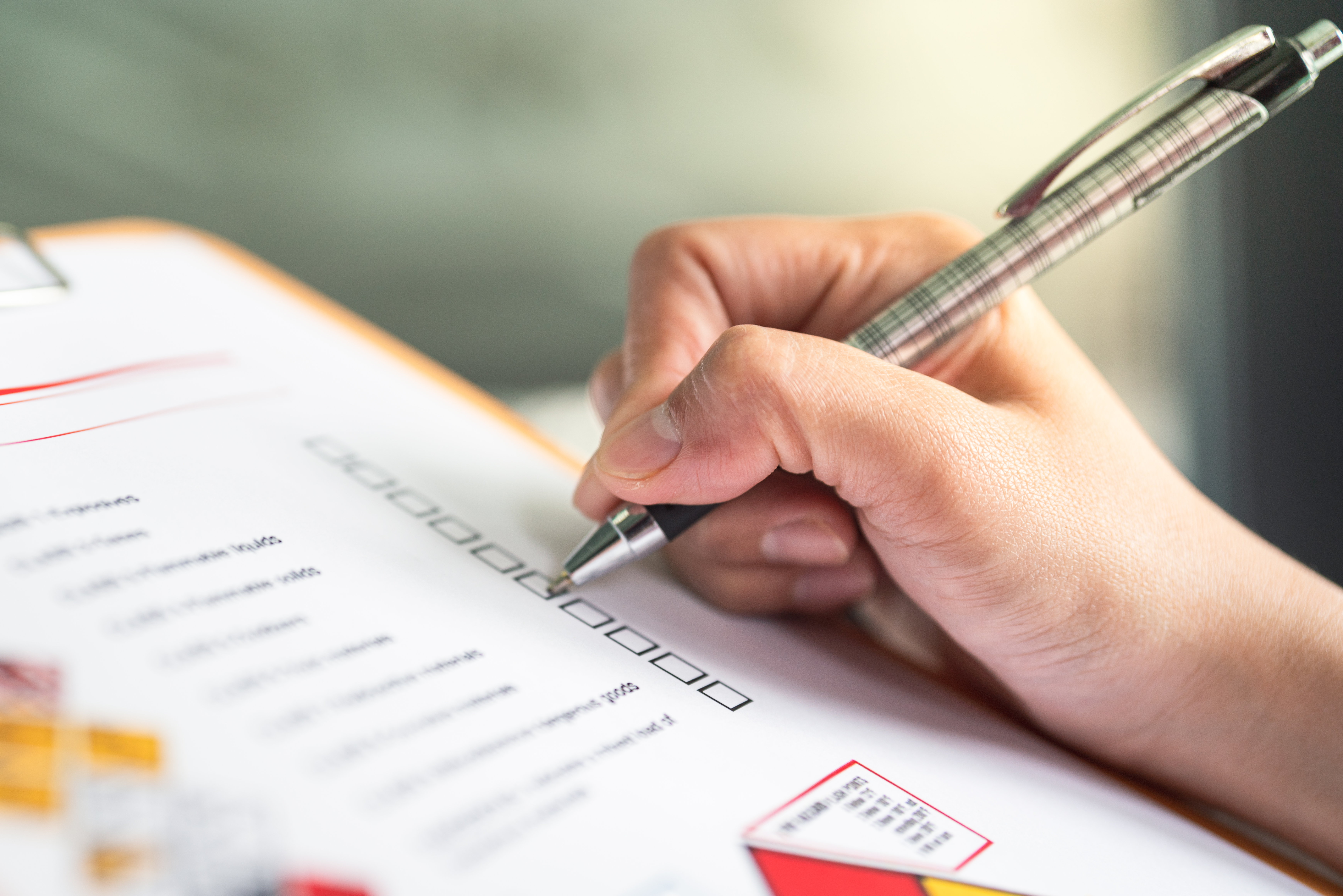 Persons hand using a pen to check boxes on a checklist